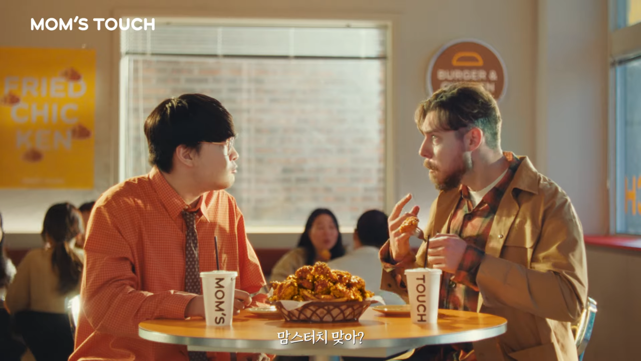 [AP신문 광고평론 No.1248] ​​​​​​​치킨을 먹으며 감탄하는 두 모델. 사진 맘스터치 유튜브 캡처ⓒAP신문(AP뉴스)