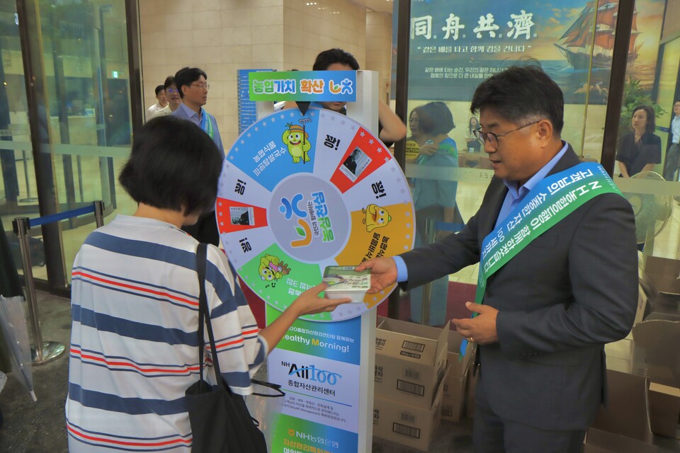 ©AP신문(AP뉴스)/이미지 제공 = NH농협은행 ▲지난 4일 서울 여의도국제금융센터에서 열린 ‘농심천심’ 출근길 캠페인 현장에서 이영우 NH농협은행 투자상품·자산관리부문 부행장이 고객에게 이벤트 경품을 전달하고 있다.