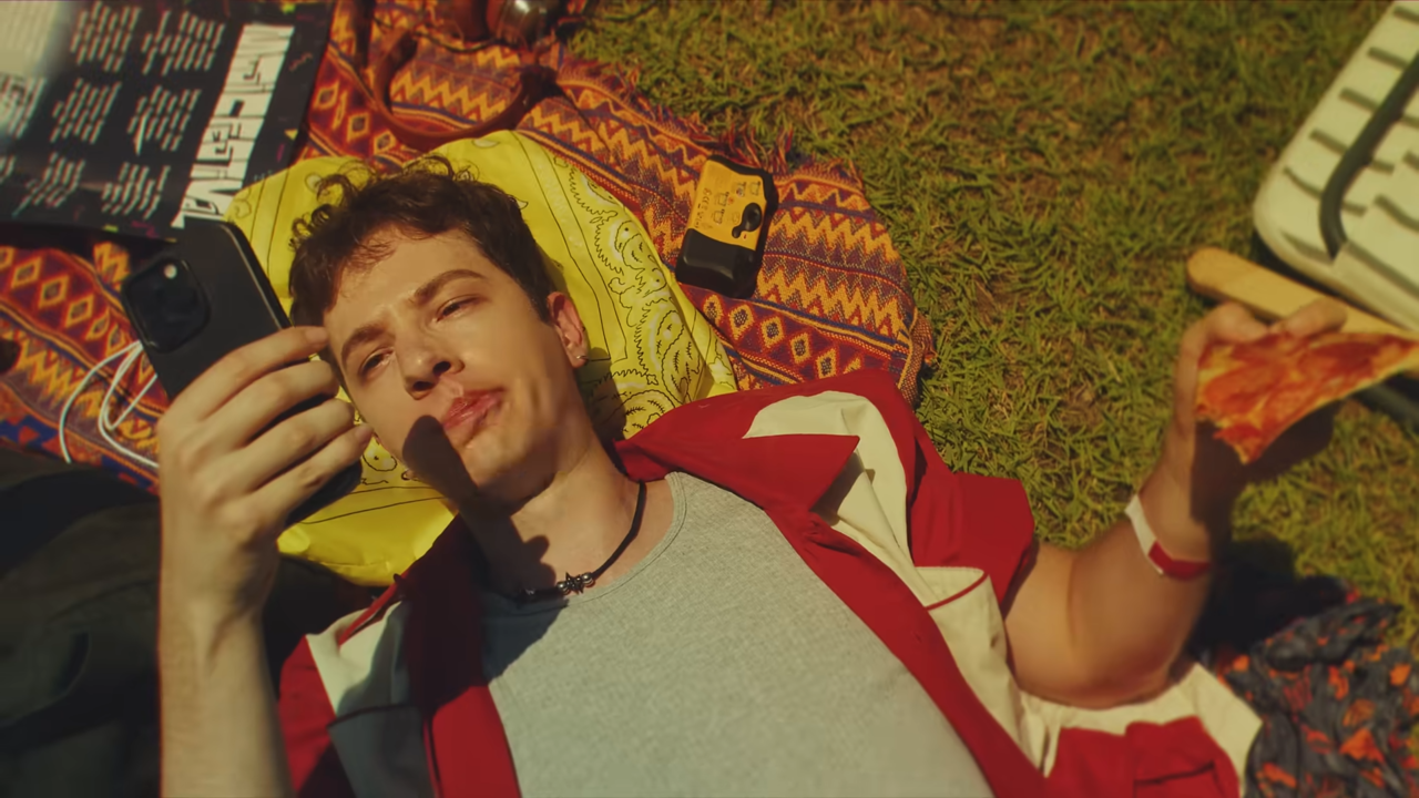 [AP신문 광고평론 No.1346]  ​​​​​​​잔디밭에 누워 따분한 표정으로 피자를 먹고 있는 사람. 사진 코카콜라 유튜브 캡처ⓒAP신문(AP뉴스)