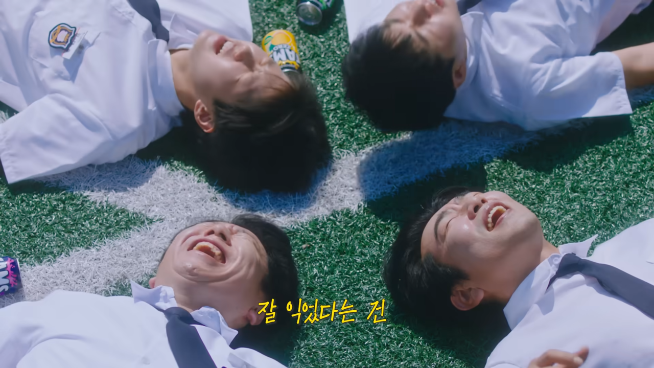 [AP신문 광고평론 No.1348]  ​​​​​​​운동장에 누워있는 김수로, 이종혁과 학생들. 사진 롯데칠성음료 유튜브 캡처ⓒAP신문(AP뉴스)