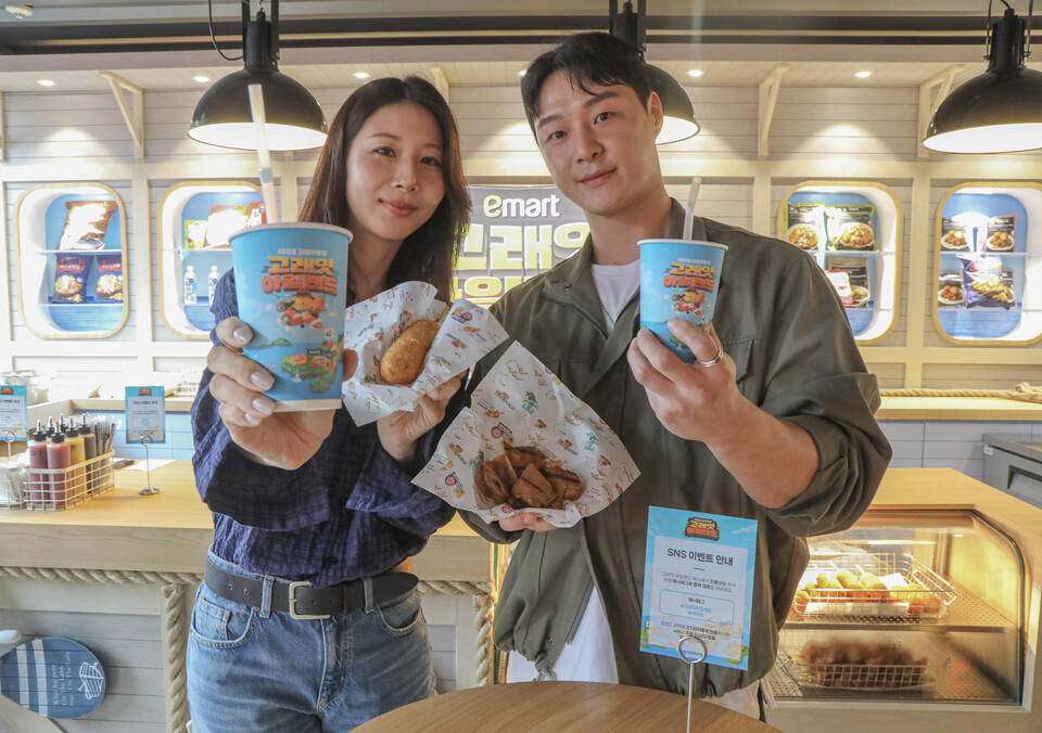 ©AP신문(AP뉴스)/이미지 제공 = 이마트 ▲이마트 '고래잇 아일랜드' 팝업 스토어에서 즐길 수 있는 먹거리를 소개 중인 모델들의 모습. 보물상자를 열어 나온 코인으로 피코크 인기 메뉴 ▲핫도그 ▲통살 닭다리 구이 ▲나쵸&칠리콘까르네를 교환할 수 있다.