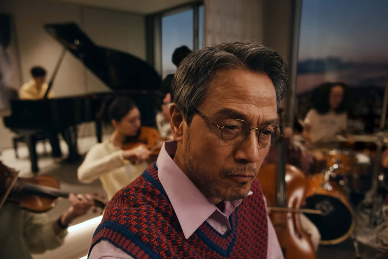 [AP신문 광고평론 No.1426]   ​​​​​​​그림 그리는 남성 주변으로 오케스트라가 에워싸고 있다. 사진 THE H 유튜브 캡처ⓒAP신문(AP뉴스)