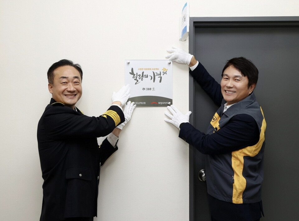 ©AP신문(AP뉴스)/이미지 제공 = KB손해보험 ▲KB손해보험 구본욱 사장(오른쪽)과 소방청 이진호 기획조정관(왼쪽)이 20일 서울 강서구 119특수구조단 119항공대에서 열린 소방공무원 심신안정실 ‘힐링의 기적 100호’ 개소식에 참여해 100호 현판을 달며 기념촬영을 하고 있다.